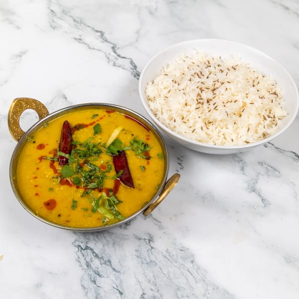 Mirch Masala's yellow lentil dal, garnished with cilantro and red chilies, served with cumin rice.