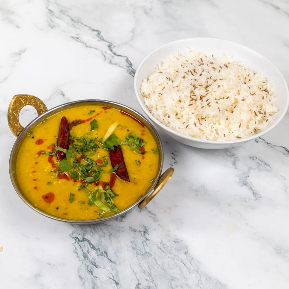 Mirch Masala's yellow lentil dal, garnished with cilantro and red chilies, served with cumin rice.
