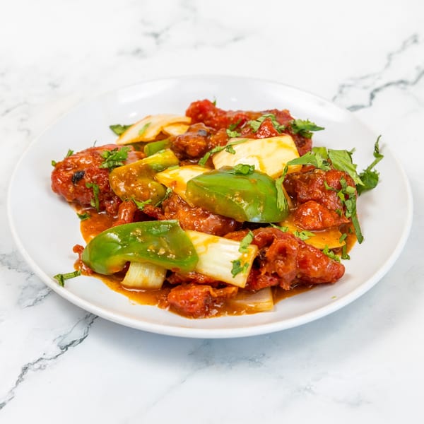 Mirch Masala Indian Restaurant's chili chicken with bell peppers and onions on a white plate.